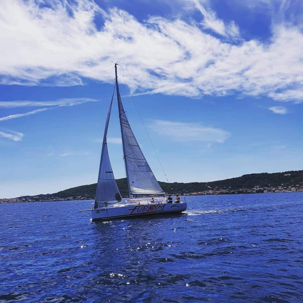 A sailboat from Marlin Sailing Academy gliding across the blue waters of the Zadar archipelago in Croatia, highlighting sailing school programs, beginner and advanced sailing courses, skipper courses, and daily sailing tours. Perfect for Zadar day trips, private day tours, sunset sailing tours, sports sailing adventures, and team building experiences.