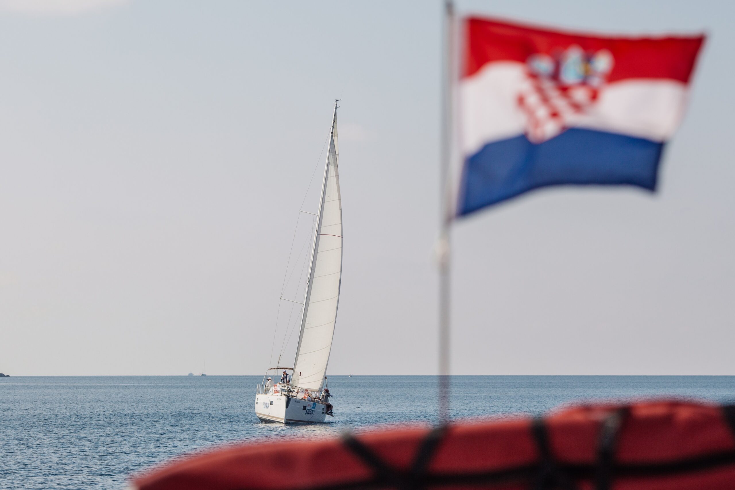 A sailboat displaying a Croatian flag glides through the waters, representing team-building activities in Zadar, Croatia.