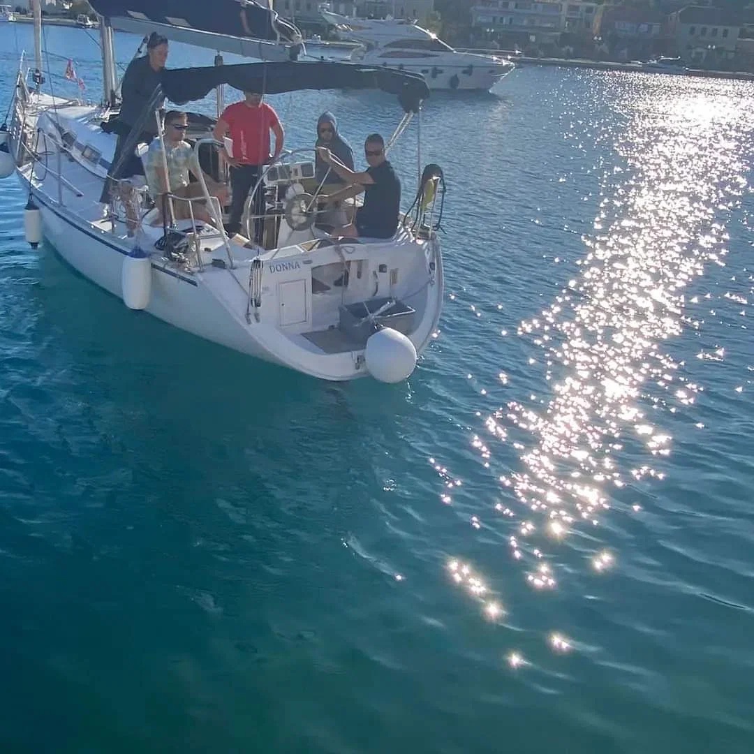 A group of people on a sailboat in clear blue waters, participating in a sailing course in Zadar, Croatia.