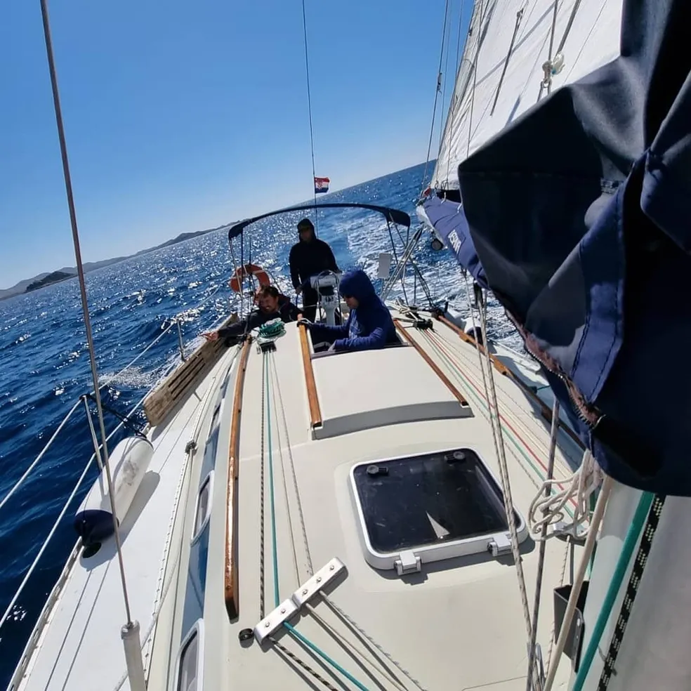 A sailboat with people on deck navigates the ocean, symbolizing adventure and learning at a sailing academy and private full day sailing tour in Zadar, Croatia.